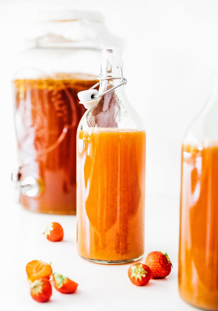 kombucha in fermentation bottles with strawberries