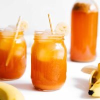 Banana kombucha in a jar with ice on a white background