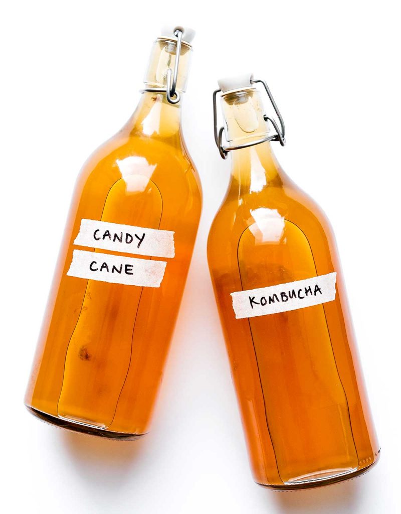 Candy cane kombucha in fermentation bottles on white background
