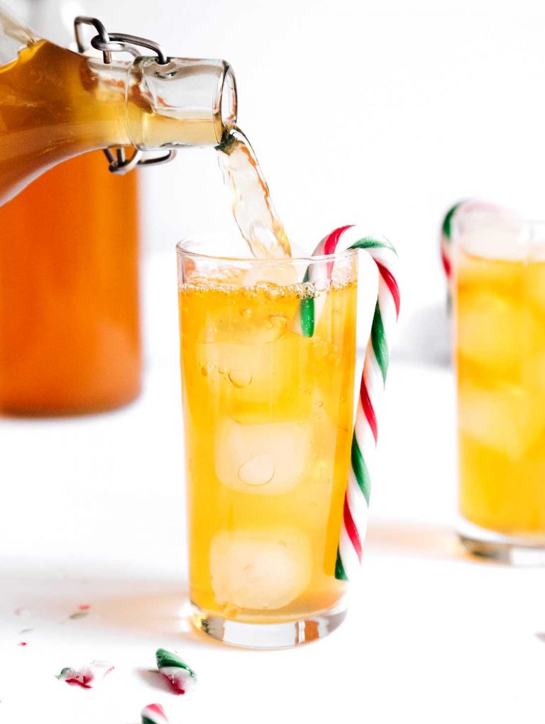 Pouring kombucha into a glass with a candy cane