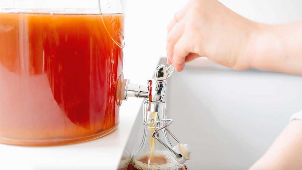 Pouring kombucha out of a spigot into a bottle