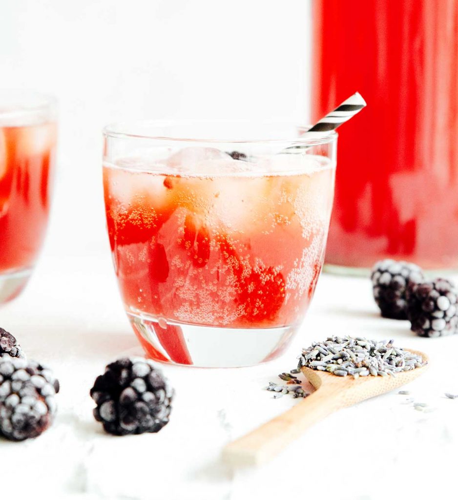 Bubbly lavender kombucha on a white background with blackberries