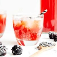 Bubbly lavender kombucha on a white background with blackberries