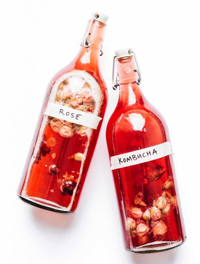 Fermentation bottles of rose kombucha on a white background