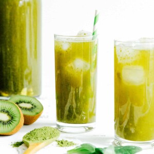 Green kombucha in a glass with a paper straw on a white background