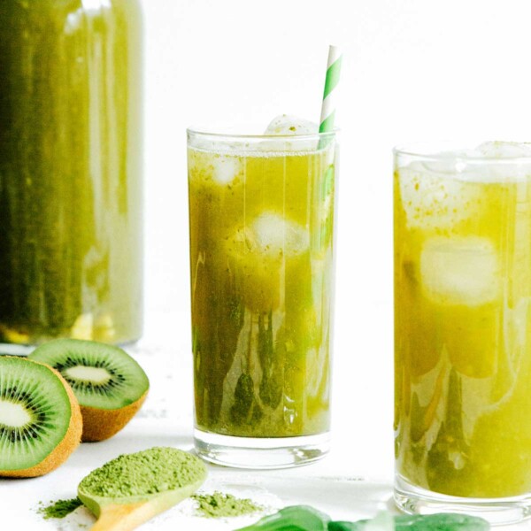 Green kombucha in a glass with a paper straw on a white background