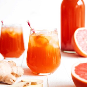 Pouring grapefruit kombucha into a glass on a white background