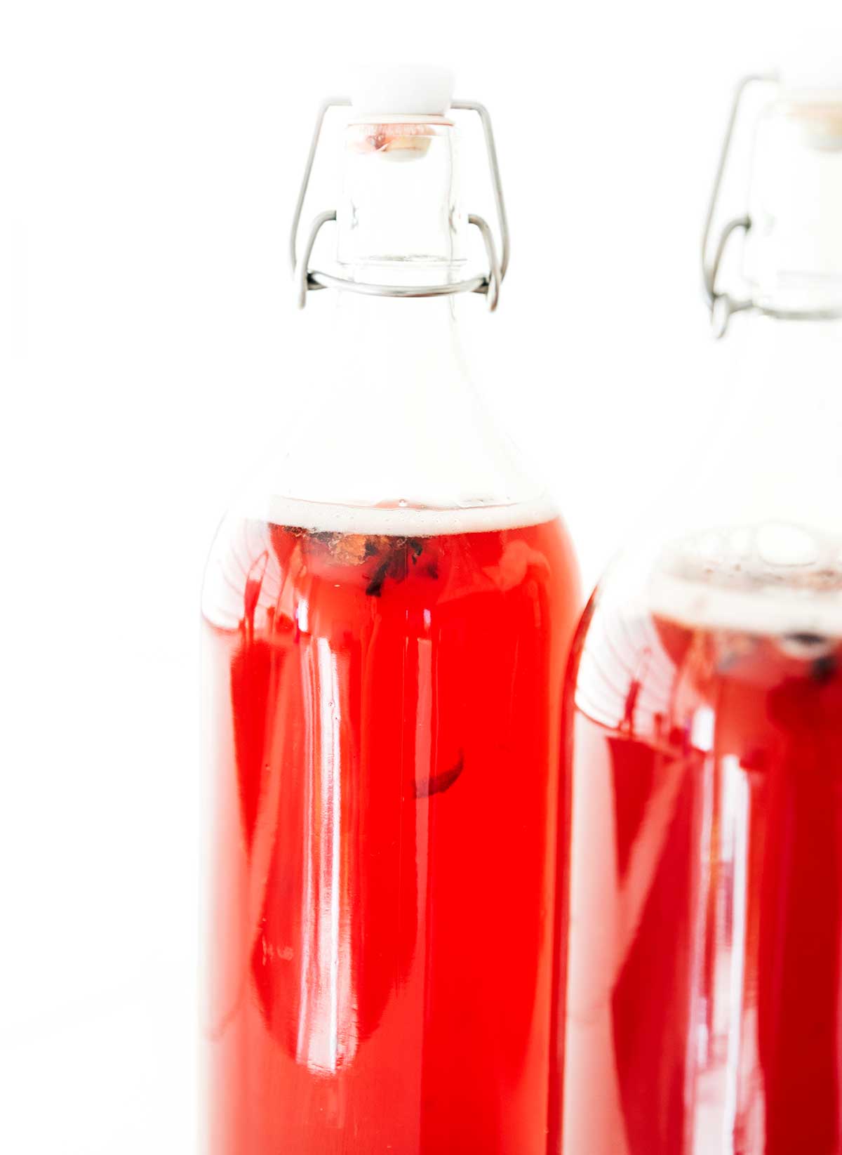 Hibiscus kombucha in fermentation bottles on a white background