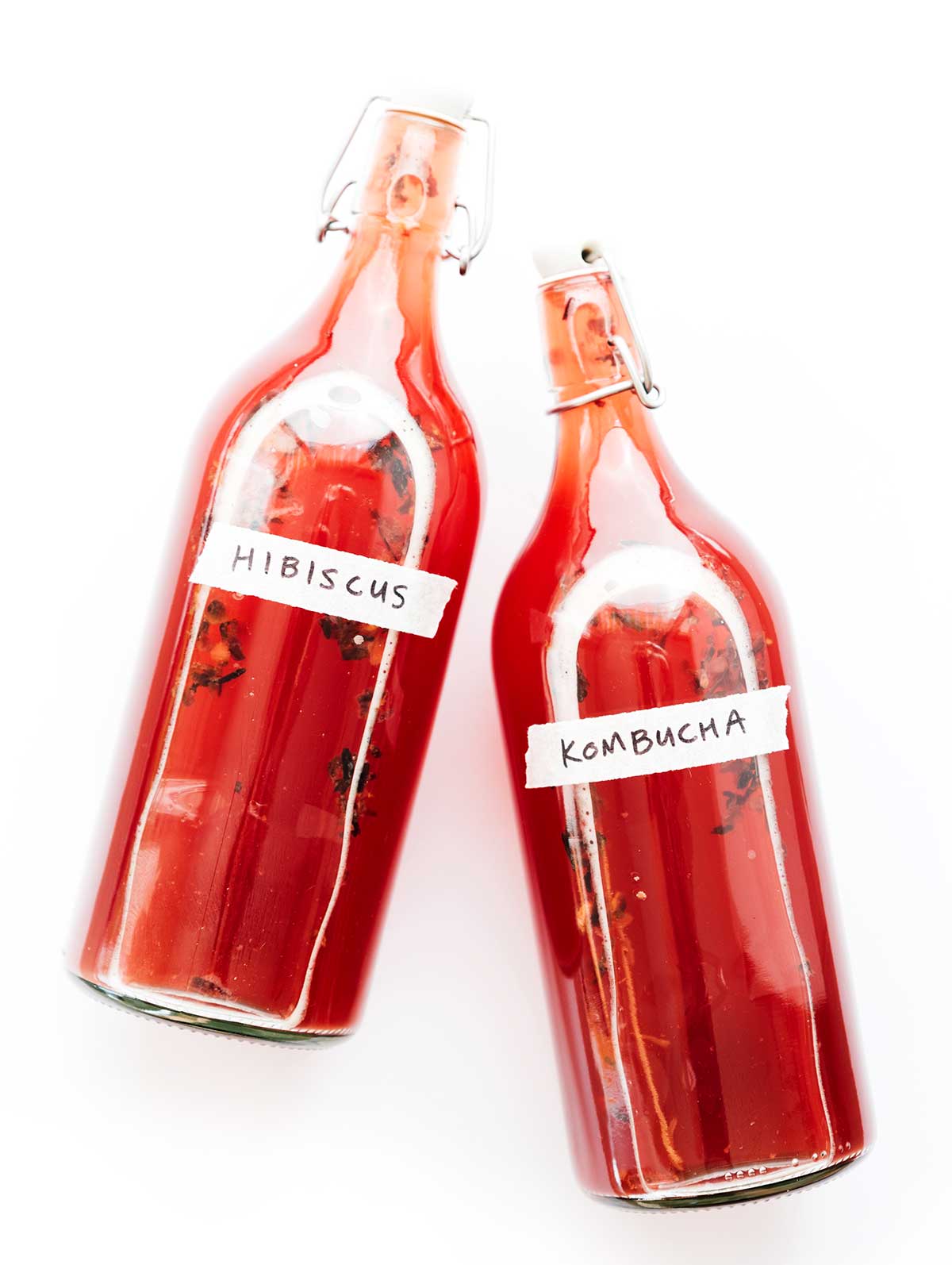 Hibiscus kombucha in fermentation bottles on a white background