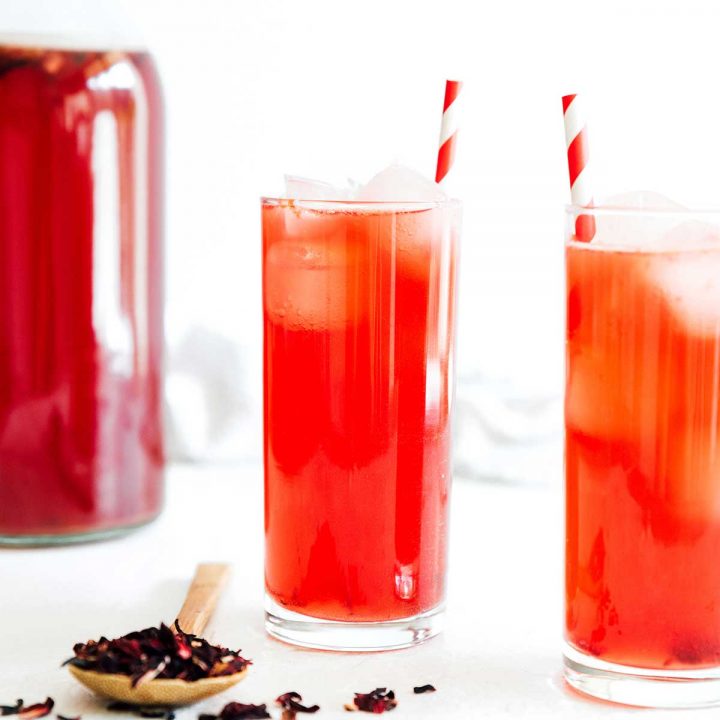 Hibiscus kombucha in a glass with a paper straw