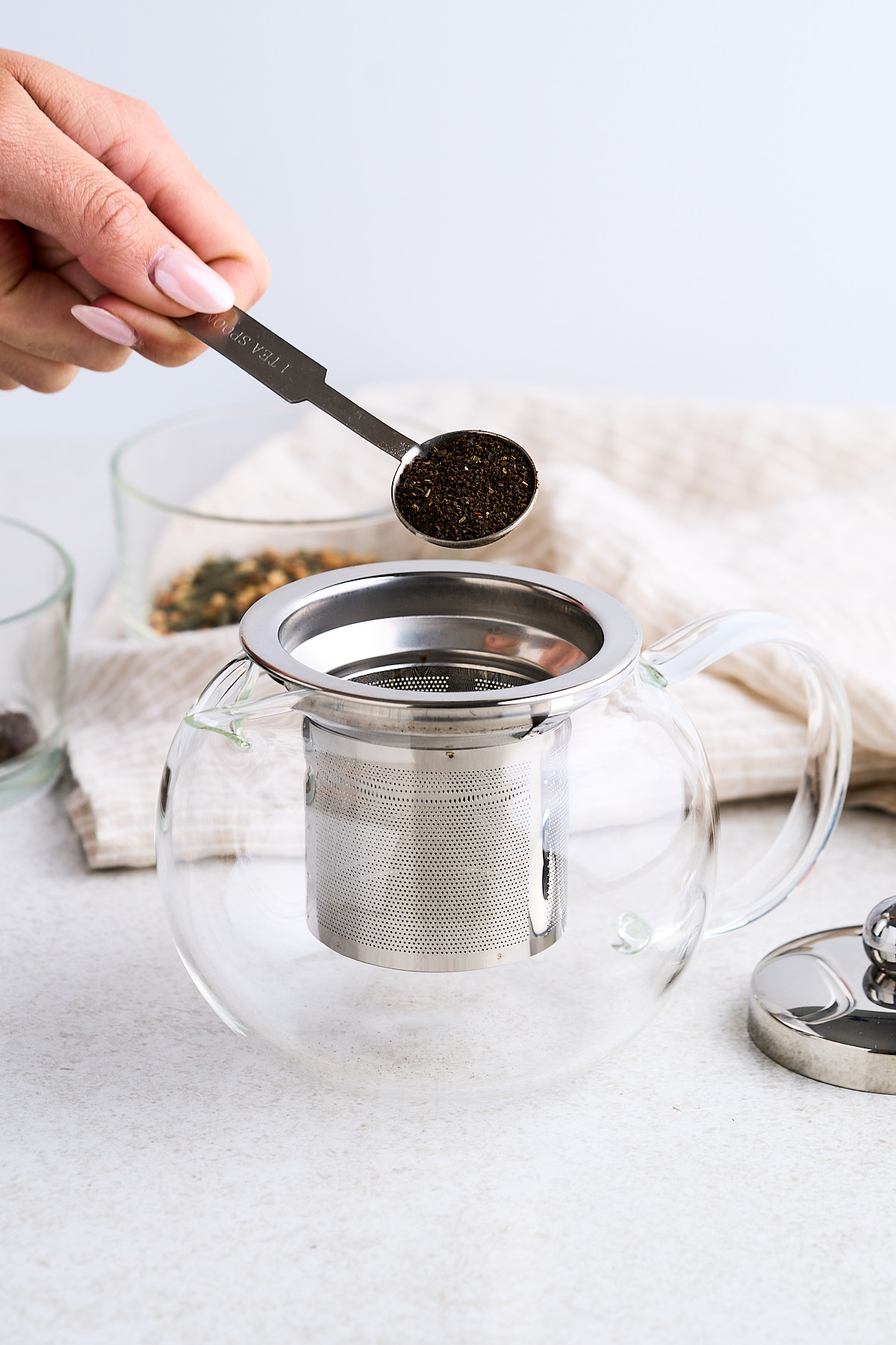 Adding tea to a glass tea pot.